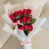 Bouquet of red roses wrapped in white paper with a pink ribbon