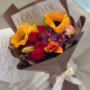 A vibrant mix of sunflowers, roses, and seasonal blooms wrapped in elegant