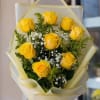 Bouquet of yellow roses with white baby's breath in pale wrapping
