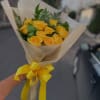 Yellow roses wrapped in beige paper with a yellow ribbon