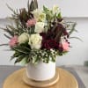 Mixed bouquet of white roses, pink carnations, and burgundy blooms in a white vase