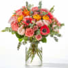 Bouquet of pink, coral, and yellow flowers in a clear glass vase