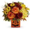 Autumn bouquet in a jack-o'-lantern vase with roses, mums, and sunflowers