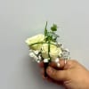 Small white rose boutonniere with baby's breath and greenery