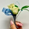 White calla lily boutonniere with blue ribbon and green leaves