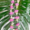 Pink flower garlands laid over large split monstera leaves