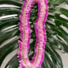 Pink lei draped over large split green leaves