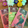 Three chocolate bars with colorful flower accents on a wooden surface.