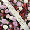 Floral arrangement with roses, chrysanthemums, and alstroemeria under a "LOVING WIFE" ribbon