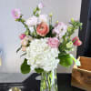 Mixed pink and white flowers arranged in a clear glass vase
