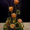 Orange roses and sunflowers in a tall floral arrangement