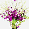 Purple orchids in a glass vase with butterfly accents