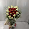 Red and white rose bouquet with baby’s breath in a glass vase and teddy bear