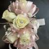 Cream roses with pink ribbon loops and small white filler flowers