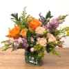 Mixed bouquet of orange and blush roses in a square glass vase