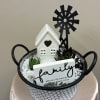 Succulent arrangement in a handled basket with a small house and family sign