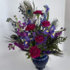 Purple and pink floral arrangement in a blue vase with peacock feathers
