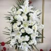 Tall white floral standing spray with lilies and chrysanthemums on an easel