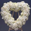 Heart-shaped white floral wreath on a wooden easel