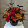 Halloween bouquet with red and orange flowers in a black vase