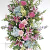 A beautifully arranged standing spray done in pastel colors with a pop