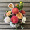 Fall floral arrangement in a white pumpkin container with colorful blooms and a pumpkin pick