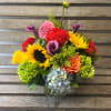 Mixed bouquet in a clear glass vase with sunflowers, calla lilies, and hydrangea