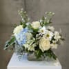 White and blue floral arrangement in a clear glass vase