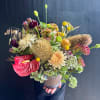 Mixed bouquet in a ribbed vase with red anthurium, cream blooms, and yellow accents