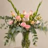Pink roses and pale blooms arranged in a clear glass vase