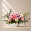 An elegant garden-inspired arrangement in blush pink, ivory, and fresh greenery with