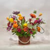 Colorful mixed flower arrangement in a wicker basket with a pearl garland