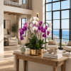 Purple and white orchids arranged in a gold planter on a coffee table