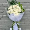 Bouquet of white roses wrapped in white paper with a green ribbon