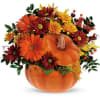 Autumn floral arrangement in a pumpkin-shaped container with orange and burgundy blooms