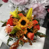 Bouquet of orange roses, sunflowers, and yellow lilies with a fall ribbon