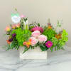 Mixed flower arrangement in a white wooden box with pink roses and bright green blooms