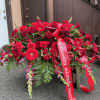 This large, broad spray features layered clusters of roses, carnations, and trailing