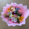 Mixed bouquet with pink, purple, and orange flowers wrapped in pink paper