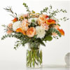 Peach roses and white mums in a clear glass vase