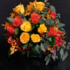 Bouquet of yellow and red roses with autumn leaves in a vase
