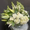 White roses and lilies arranged in a clear glass vase