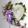 Heart-shaped floral wreath with pink roses and white flowers on a stand