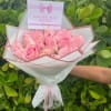 Bouquet of pink roses wrapped in white paper with a pink ribbon