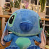 Large blue plush Stitch toy sitting in a flower shop display