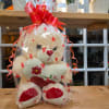 Cream teddy bear in heart-print cellophane with a red bow