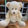 White teddy bear with a paw-print ribbon sitting in a glass container