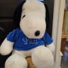 Large Snoopy plush toy wearing a blue shirt that says SMILES