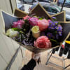Handheld bouquet of pink, lavender, and white roses with purple filler flowers
