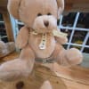 Plush teddy bear with a ribbon bow sitting in a glass jar